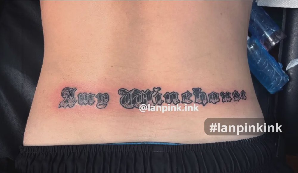 Hình xăm chữ Amy Winehouse ở thắt lưng phong cách Old English gần hõm Venus tại Lan Pink Tattoo