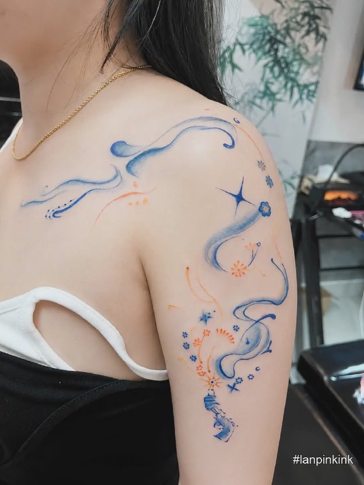 Hình xăm khói họa tiết màu xanh cam trải dài từ vai xuống bắp tay nữ, kết hợp hoa nhỏ và đường nét mềm mại
